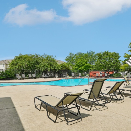a swimming pool with chairs and trees